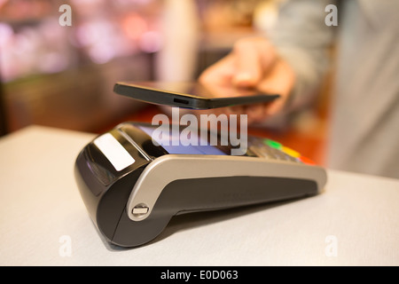 Female paying cellphone shop butcher Stock Photo