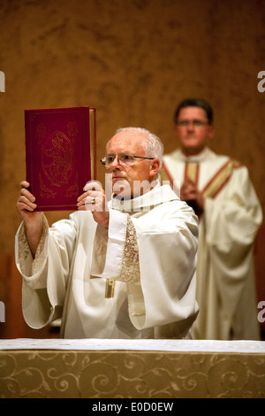 An elderly deacon holds the gospel during the Great Easter Vigil mass at St. Timothy's Catholic Church, Laguna Niguel, CA. Note pastor in background. Stock Photo