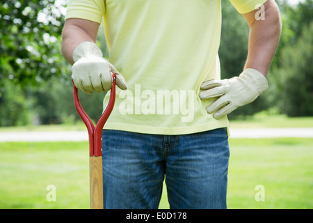 man with gardening tool standing in back yard Stock Photo