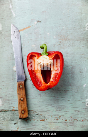Half red sweet pepper and knife on blue background textural Stock Photo