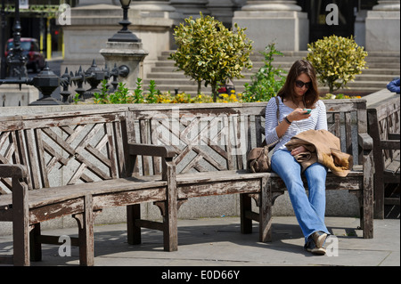 A young woman texting on moblie telephone, London, England, United Kingdom. Stock Photo
