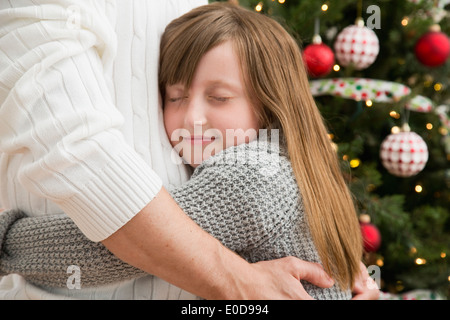 Father and daughter (8-9) embracing near Christmas tree Stock Photo