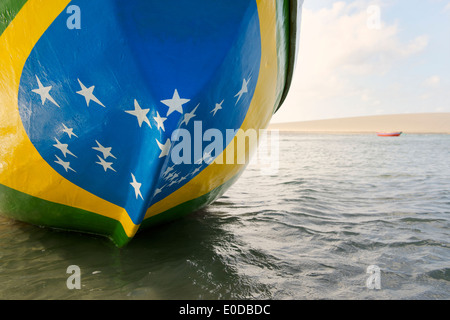 Fishing boat painted with bright Brazilian flag colors on the beach in Jericoacoara Brazil Stock Photo