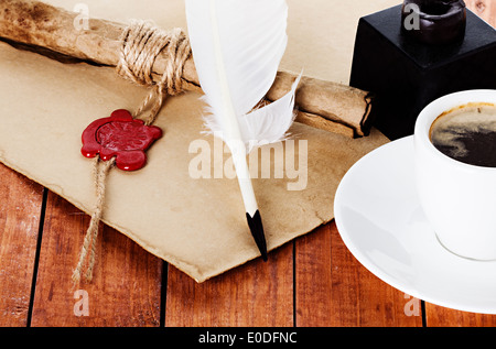 cup of coffee with a quill pen and inkwell parchment scroll on wooden background Stock Photo