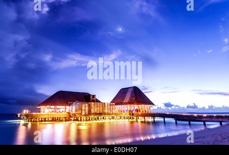 Beach restaurant glowing with bright lights in the night, romantic place for date on tropical island, summer holidays concept Stock Photo