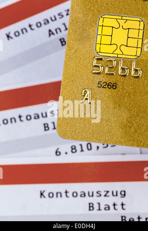 A golden credit card and bank statement. Symbolic photo for cashless shopping and status symbols., Eine goldene Kreditkarte und Stock Photo