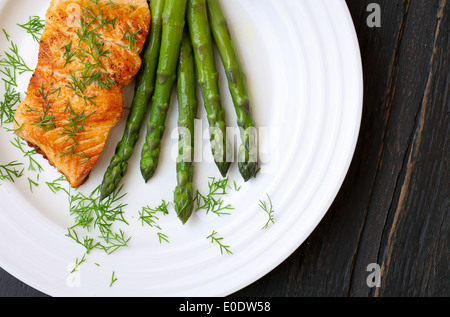 Salmon fillet with asparagus and dill on white plate dark rough wood Stock Photo