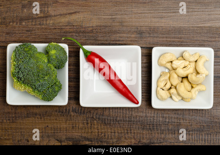 Broccoli, chili and cashew nuts in white bowls Stock Photo