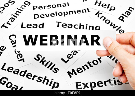 Hand holding a piece of paper with printed Webinar on it. Stock Photo