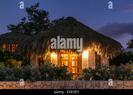 Boutique hotel cottages with thatched roof at night, Negril, Jamaica Stock Photo