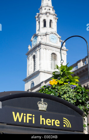 Wifi Here sign on black BT telephone box with tower of St Martin in the Fields church behind London England UK Stock Photo