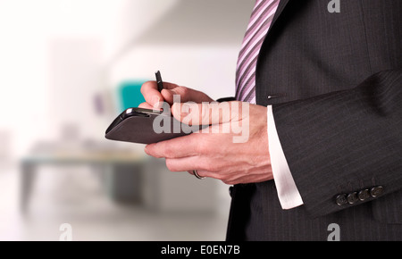 A businessman writing a message with a stylus on an electronic device. Stock Photo