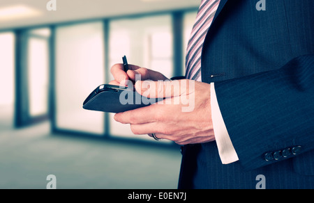 A Businessman writing a message with a stylus on an electronic device. Stock Photo