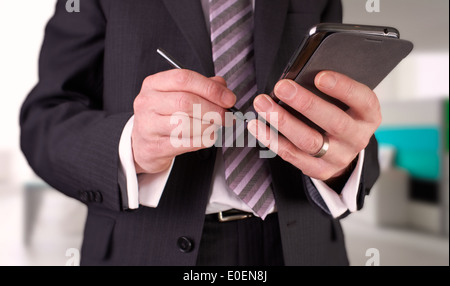 A businessman writing a message with a stylus on an electronic device. Stock Photo