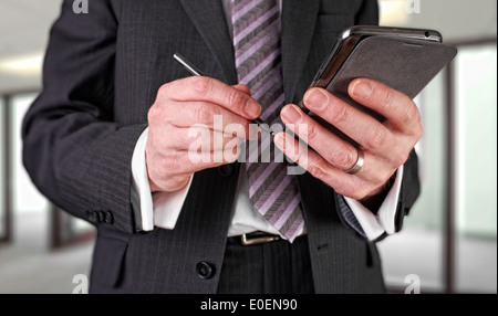 A businessman writing a message with a stylus on an electronic device. Stock Photo
