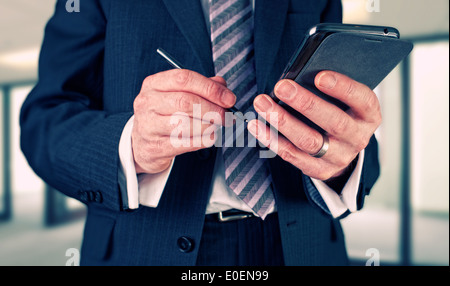 A businessman writing a message with a stylus on an electronic device. Stock Photo