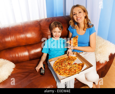 Happy boy and mother eating pizza on the couch Stock Photo