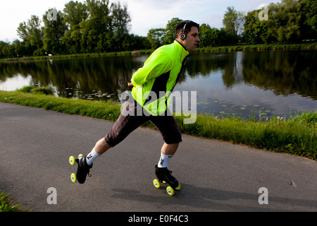 Man on the bike trail, roller skates path, man listens to music on headphones roller blading Stock Photo