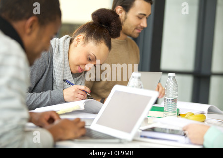Young african american woman taking notes from books for her study. Students sitting at table with books and laptop studying. Stock Photo