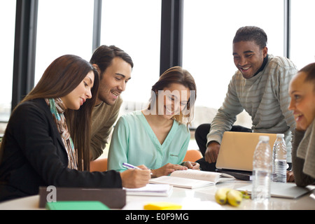 Group of multiracial young students studying together at a table. Mixed race people doing group study. Stock Photo