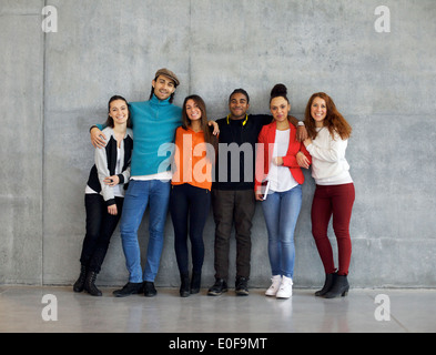 Multiethnic group of happy young university students on campus. Mixed race young people standing together against wall. Stock Photo
