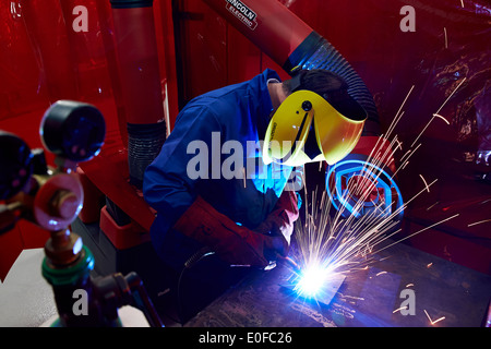 Sparks fly as a skilled worker or welder works with metal in a UK manufacturing factory. Stock Photo