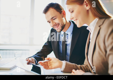 Image of two young business partners using touchpad at meeting Stock Photo