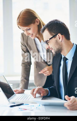 Image of two young business partners using laptop at meeting Stock Photo