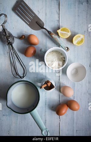 Ingredients for making pancakes, including eggs, flour cinnamon and a whisk Stock Photo