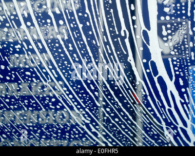 Soap suds making pattern on car windshield in car wash Stock Photo