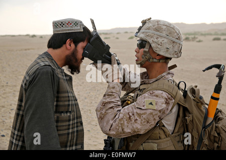 US Marines Lance Cpl. John Sanchez with the Bravo Company assault force uses a Biometric Enrollment and Screening Device to check a villager during a counter insurgency mission May 1, 2014 in Tagvreshk Village, Helmand province, Afghanistan. Stock Photo