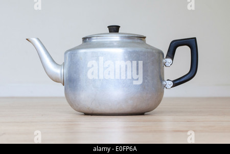 Old metal tea pot isolated on wooden table Stock Photo