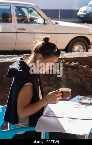 Spanish woman drinking coffee and reading newspaper outside bar. Canary Islands, Spain. Stock Photo