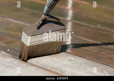 Close-up of brush with terrace oil during maintenance of teak terrace. Stock Photo