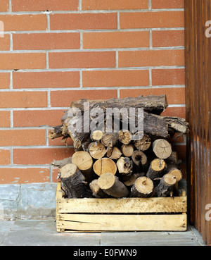 dry chopped firewood logs in a pile on the brick wall background Stock Photo