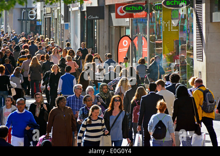 Looking down from above at famous busy shoppers Oxford Street shop fronts with crowd of backlit shopping people walking in West End London England UK Stock Photo