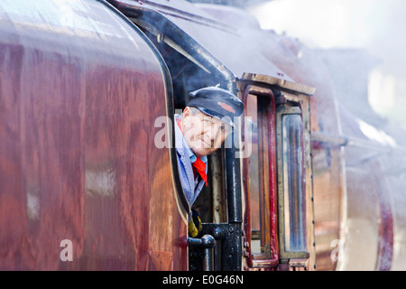 A steam engine driver looking out of his engine on the Great Central Railway at Rothley in Leicestershire Stock Photo