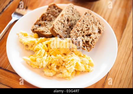 Breakfast of banana bread and scrambled eggs on a white plate Stock Photo