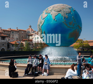 Girls posing for a photo at Earth globe fountain in Tokyo Disney restort Disneysea theme park, Japan Stock Photo