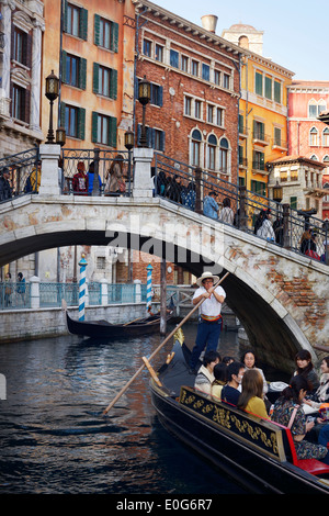 People taking a ride in a Venetian gondola passing under a bridge at Tokyo Disneysea Mediterranean harbor. Japan. Stock Photo