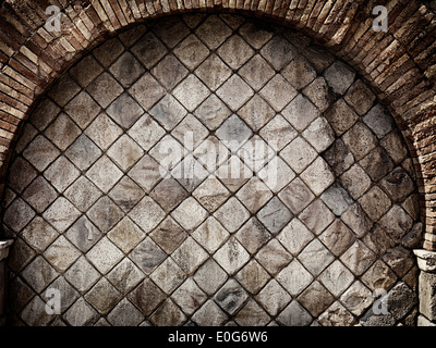 Old rustic stone wall with brick arch grungy texture background Stock Photo