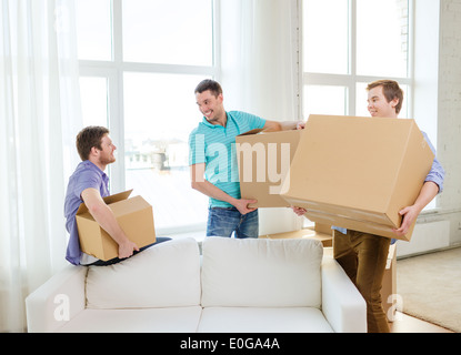 smiling male friends carrying boxes at new place Stock Photo