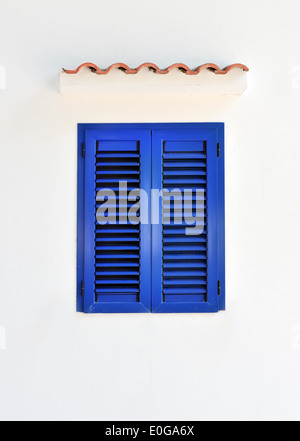 Closed window with blue shutters on white wall Stock Photo