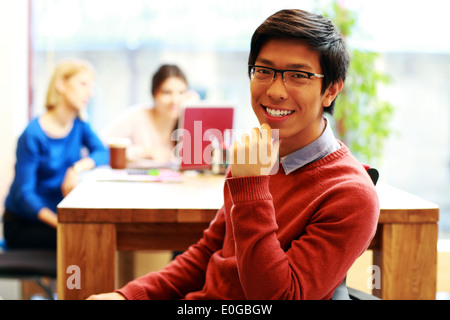 Young happy asian student sitting at the table Stock Photo