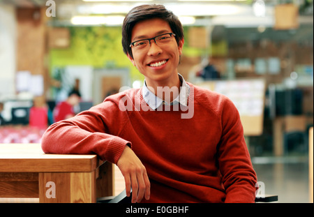 Young cheerful asian student sitting at the table Stock Photo