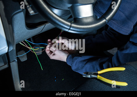 A man wearing a hoody hot wiring a car. Stock Photo
