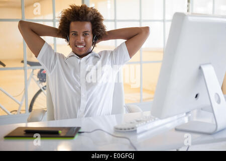 Smiling young businessman using digitizer and headset at desk Stock Photo