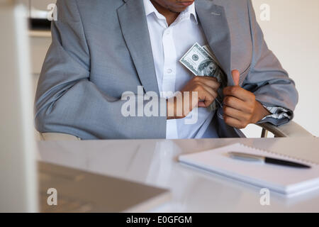 Dodgy businessman pocketing wad of dollars Stock Photo