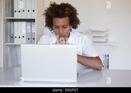 Focused casual businessman using laptop at desk Stock Photo