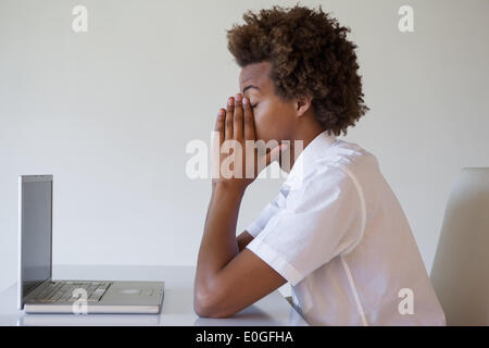 Casual businessman feeling exhausted at his desk Stock Photo